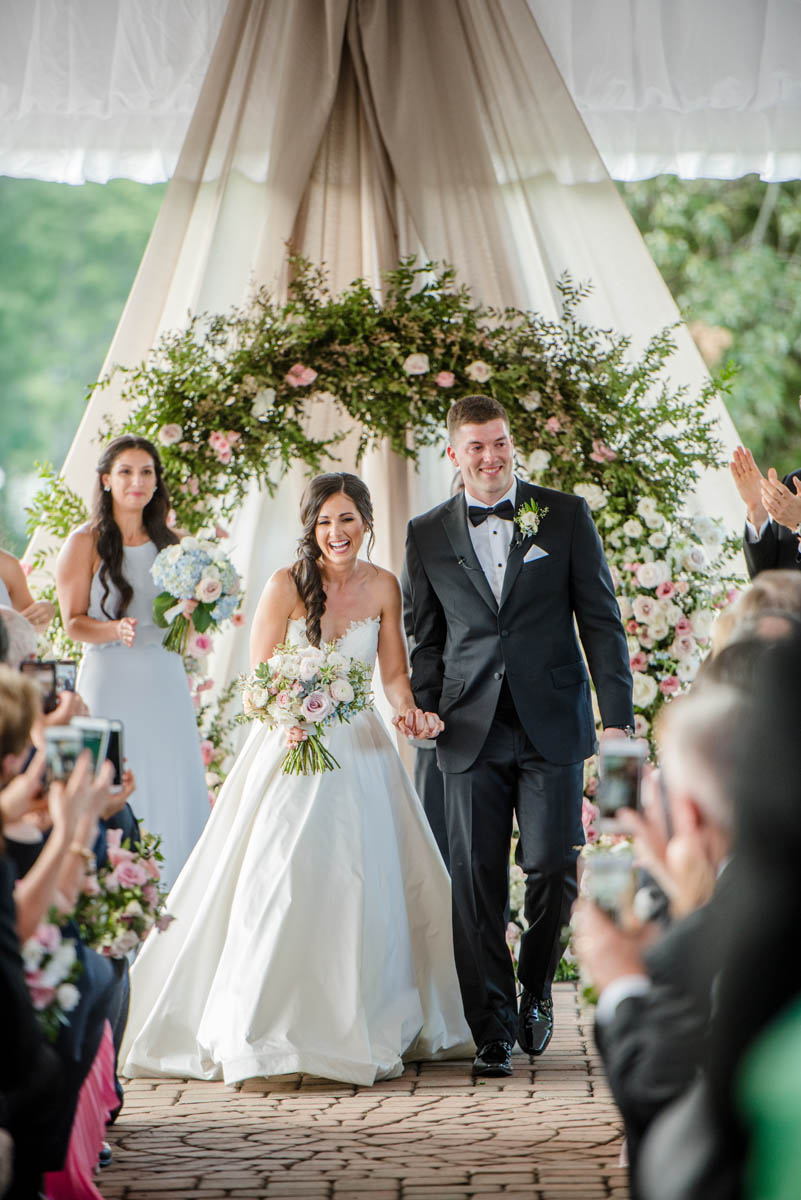 Bride and groom walking down aisle at Angus Barn tented wedding